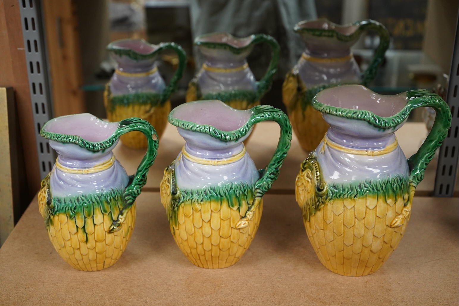 A graduated set of three maiolica ram decorated jugs, tallest 23cm high.